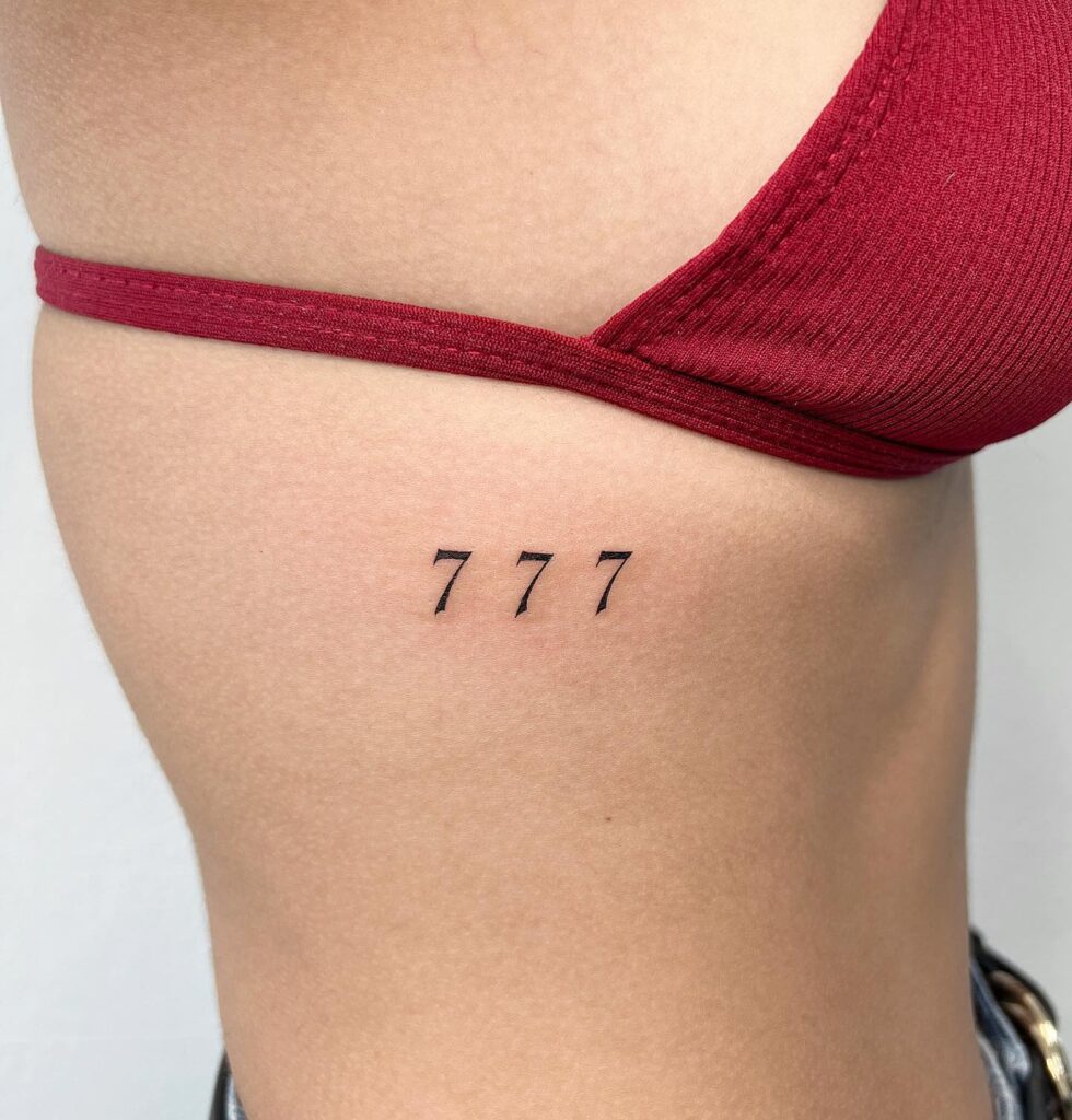 Stunning 777 number rib tattoo for females, featuring thoughtful spacing between digits ribbons of fortune 