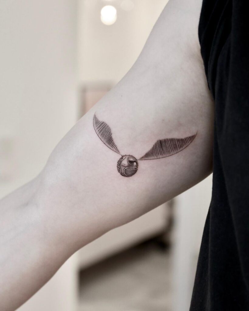 Stunning inner bicep golden snitch tattoo idea intricate beauty