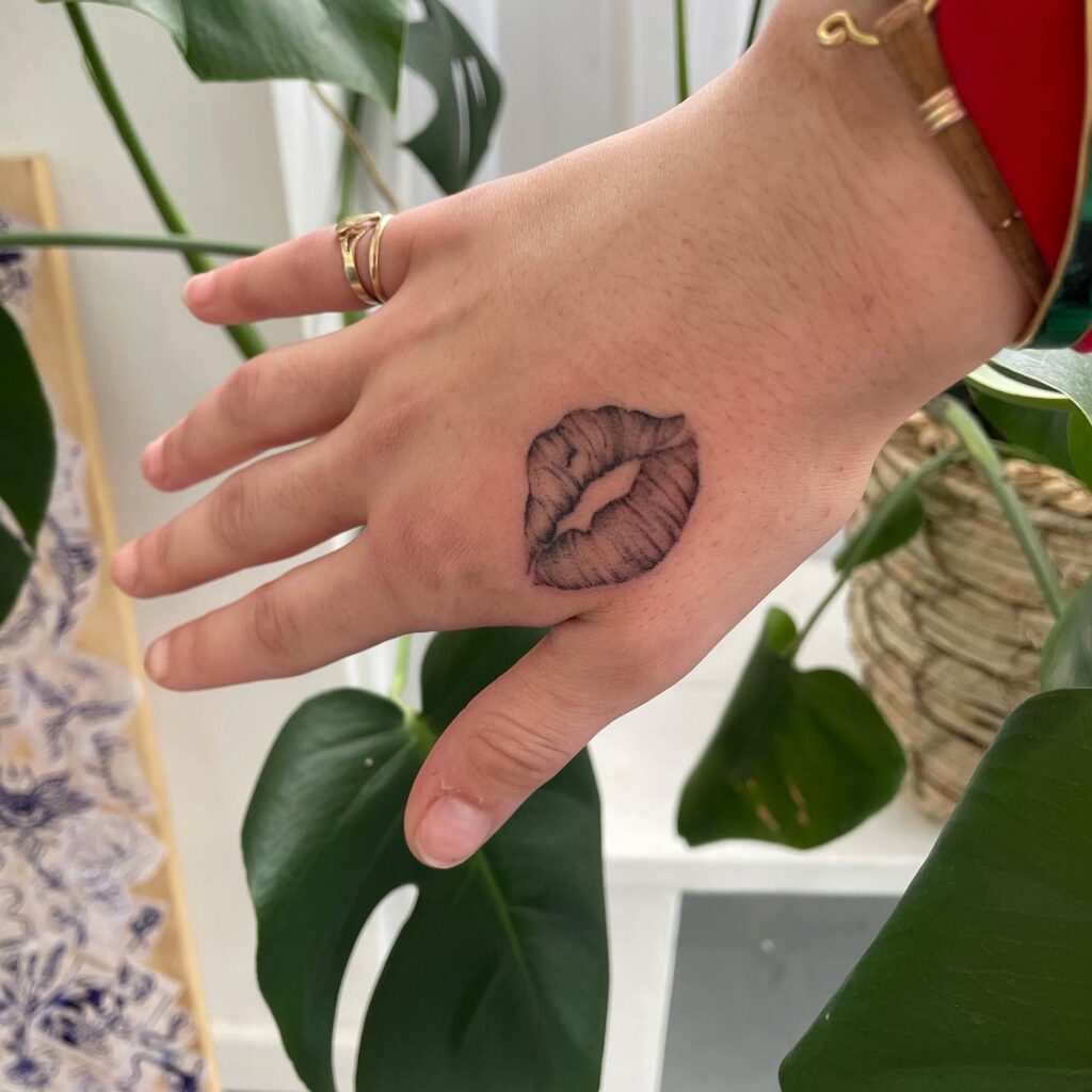 Stunning kiss lip tattoo on the hand a playful touch