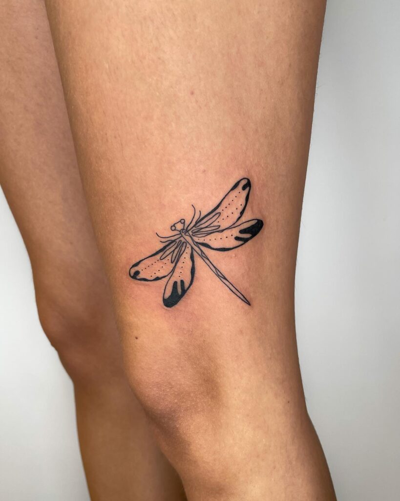 Stylized Dragonfly Upper Leg Tattoo with Bold Black Shading and Fine Line Details