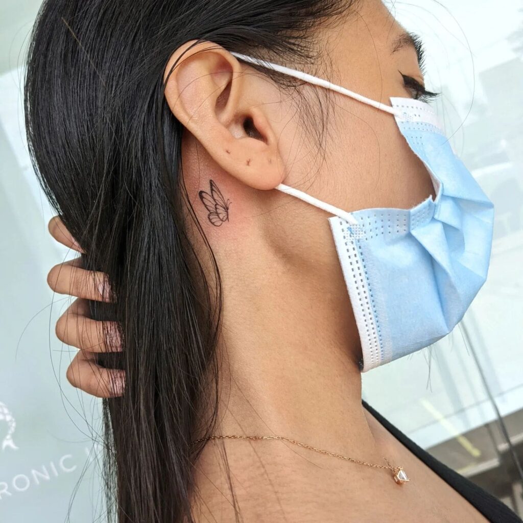 Subtle elegance miniature butterfly tattoo gracing the ears nape
