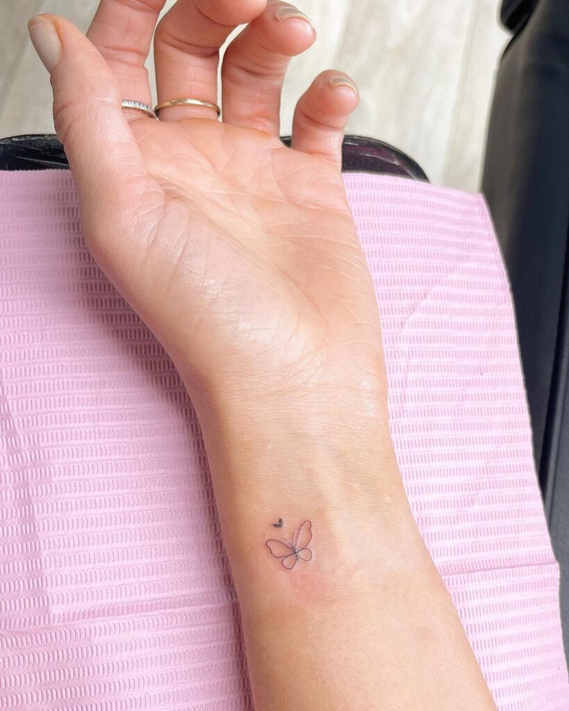 Subtle outline butterfly and small black heart on inner wrist