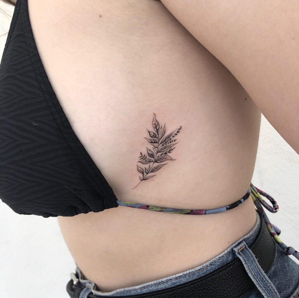 Super delicate branch of leaves tattoo on the rib: detailed and intricate foliage design