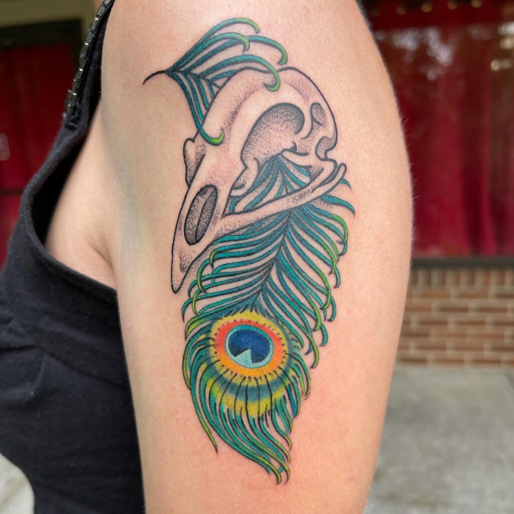 Symbolic fusion upper arm tattoo featuring birds kull and peacock feather for women