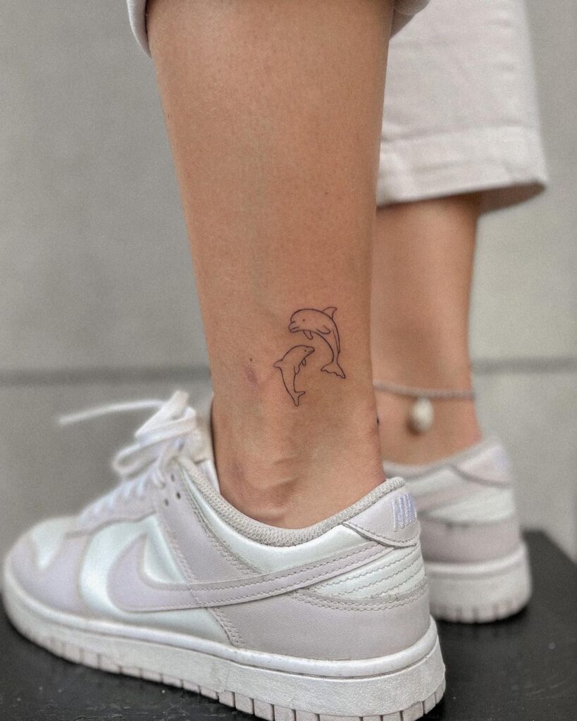 Thin outline dolphins tattoo above the ankle ankle aquatics