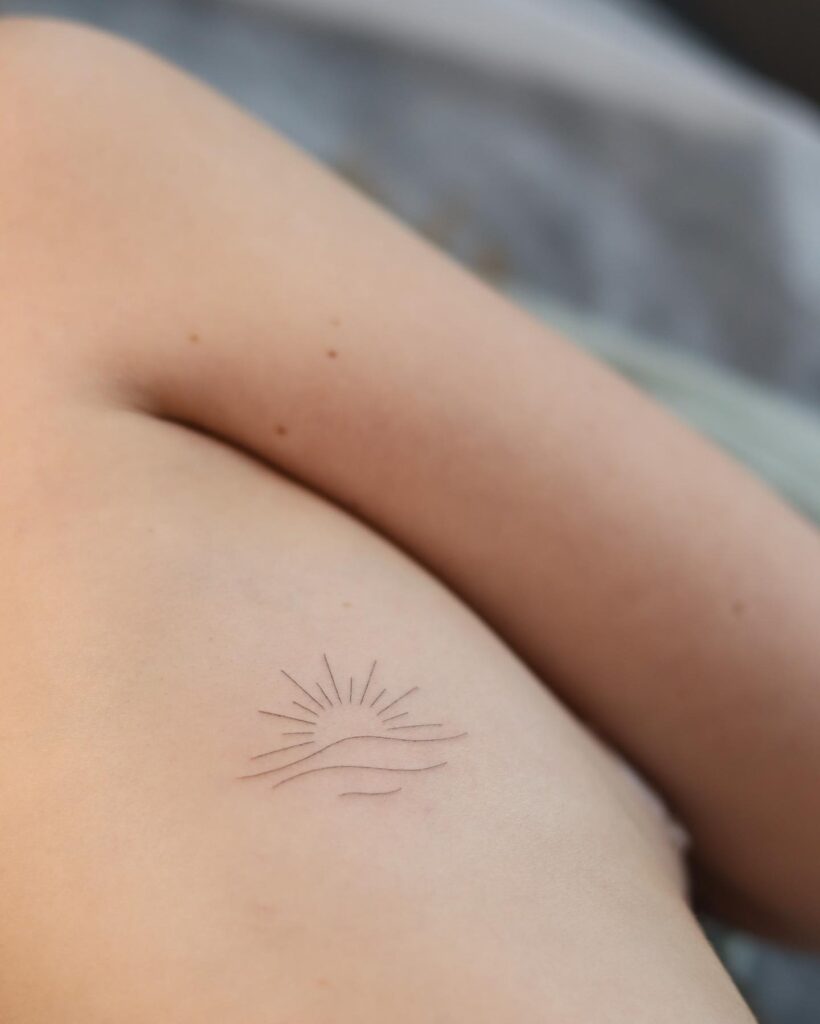Thinline rib sun and wave tattoo subtle beauty