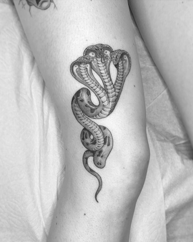 Three-headed cobra tattoo adorning the side of the knee a unique female design