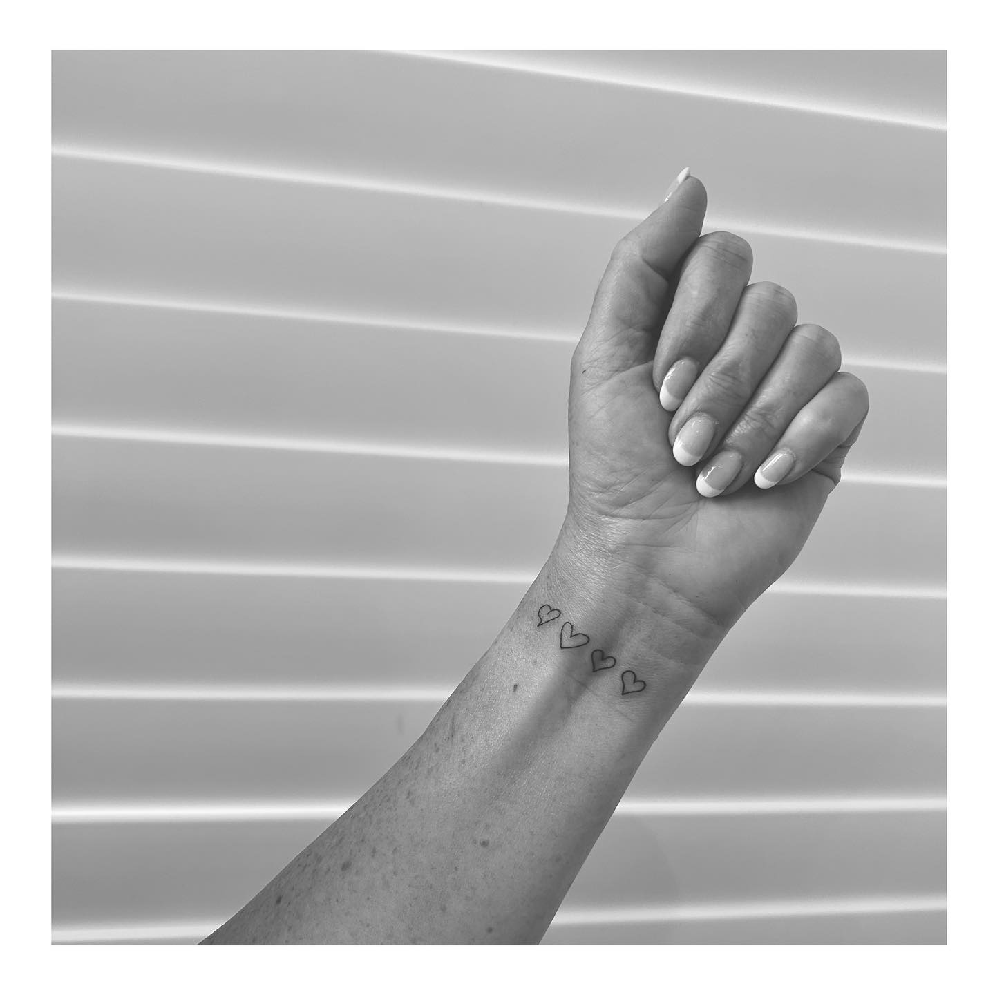 Four Minimalist Heart Outline Tattoos on Wrist Representing Love & Connection