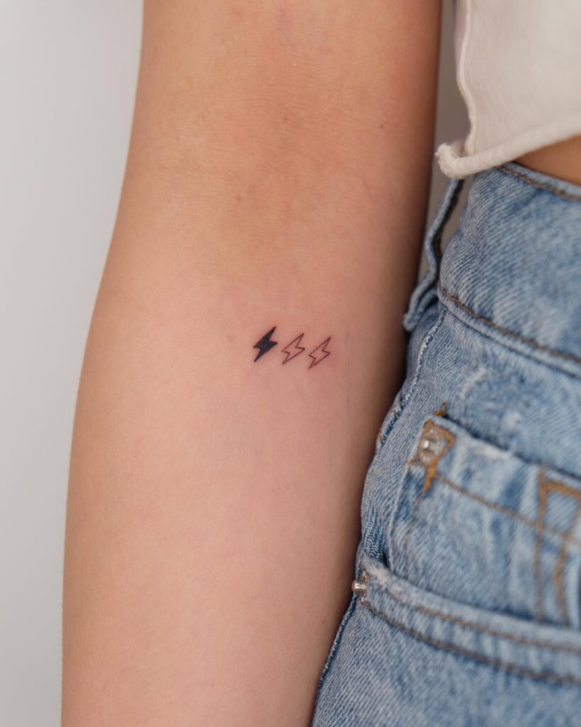 Three Small Lightning Bolts in a Row Tattoo Below the Elbow, a Mix of Black Fill and Sleek Outlines: Electric Elegance
