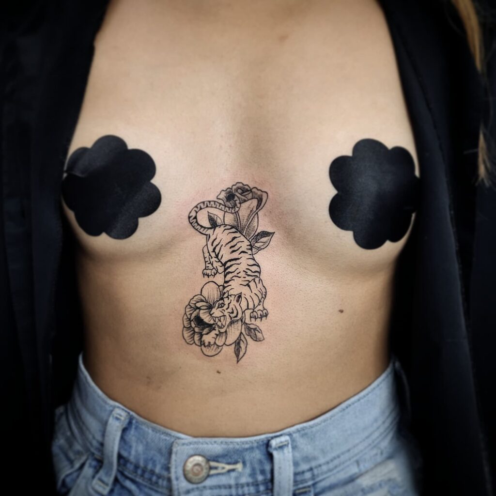 Tiger and floral sternum tattoo symbolizing strength and femininity