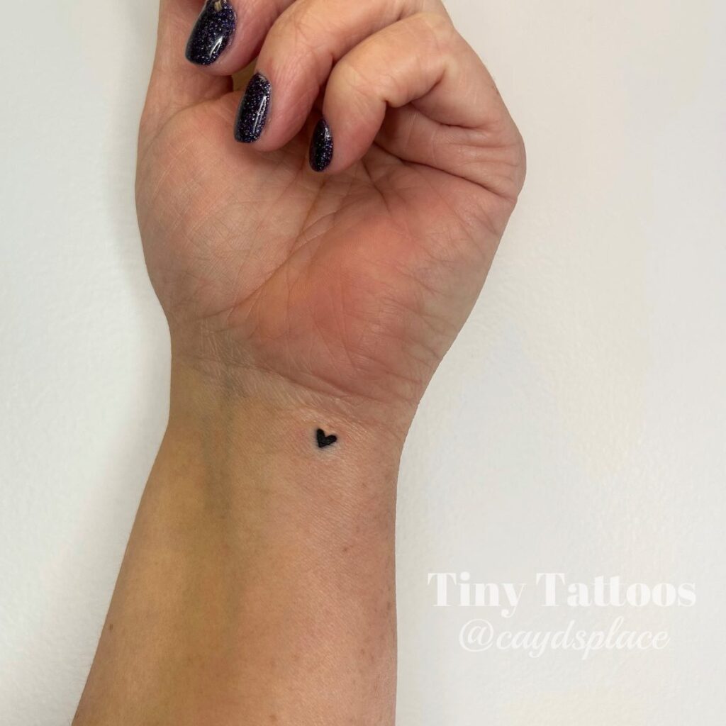 Tiniest love heart tattoo filled with black a delicate addition to the inner wrist wrist whispers