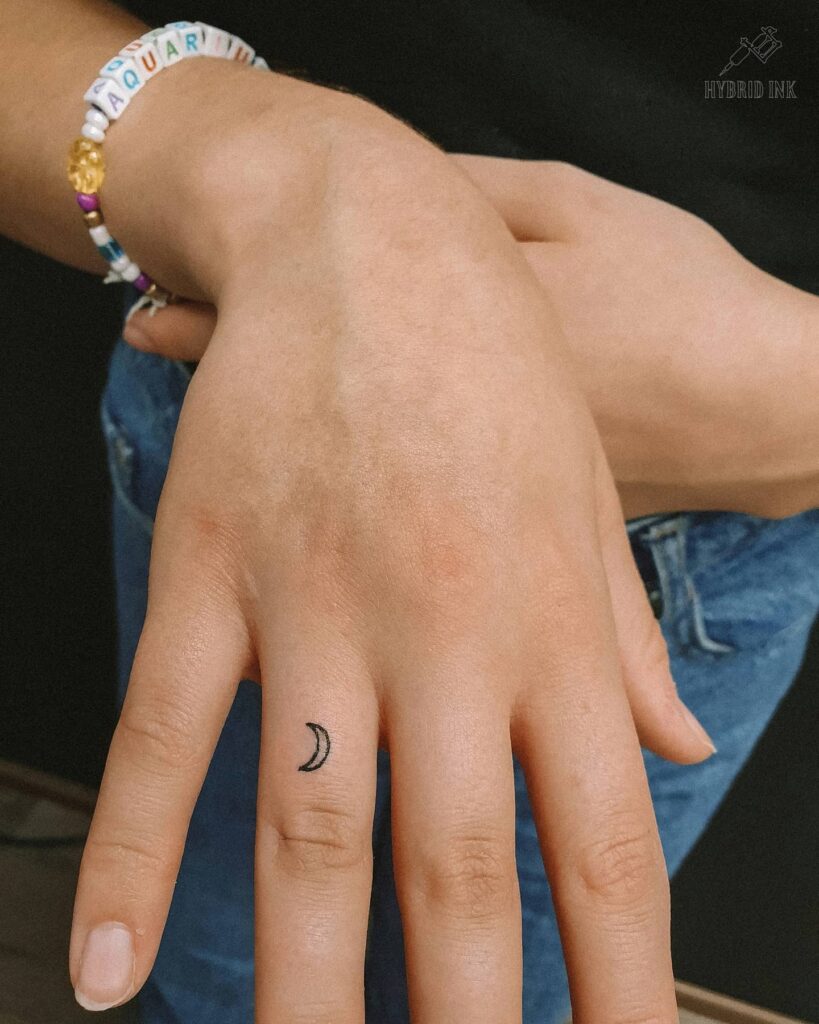 Tiny Crescent Moon on the Outer Ring Finger, Outlined in Blackwork for a Subtle Celestial Touch: Lunar Gleam