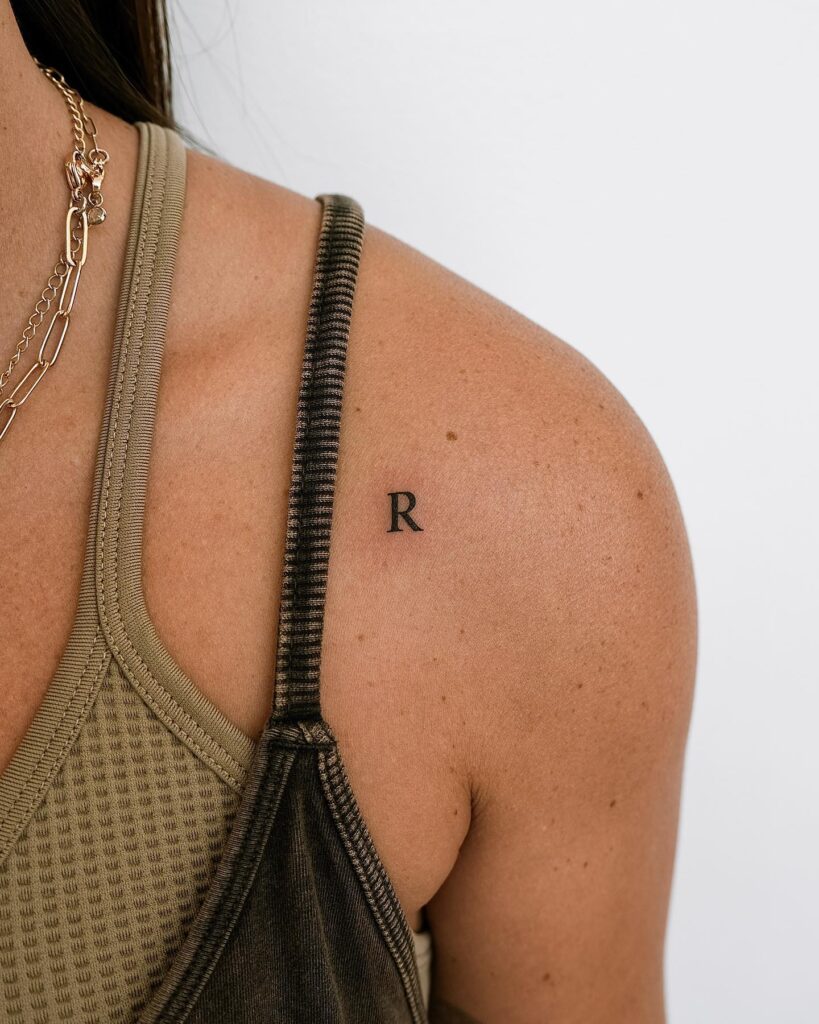 Tiny "R" letter tattoo on the shoulder: subtle personalization