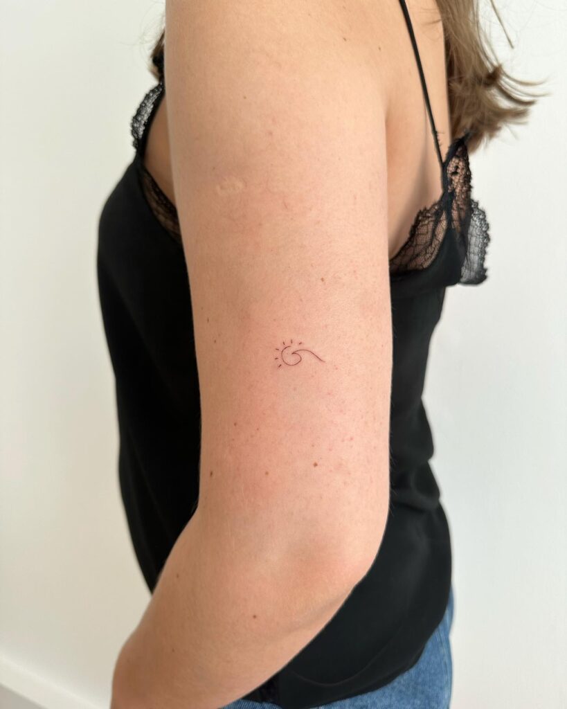 Tiny above elbow wave and sun tattoo female chic