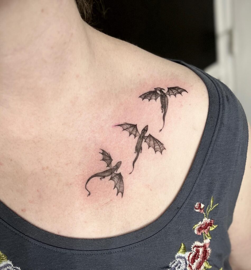 Tiny black ink dragons tattoo on the collarbone, each unique and delightful dragons trio