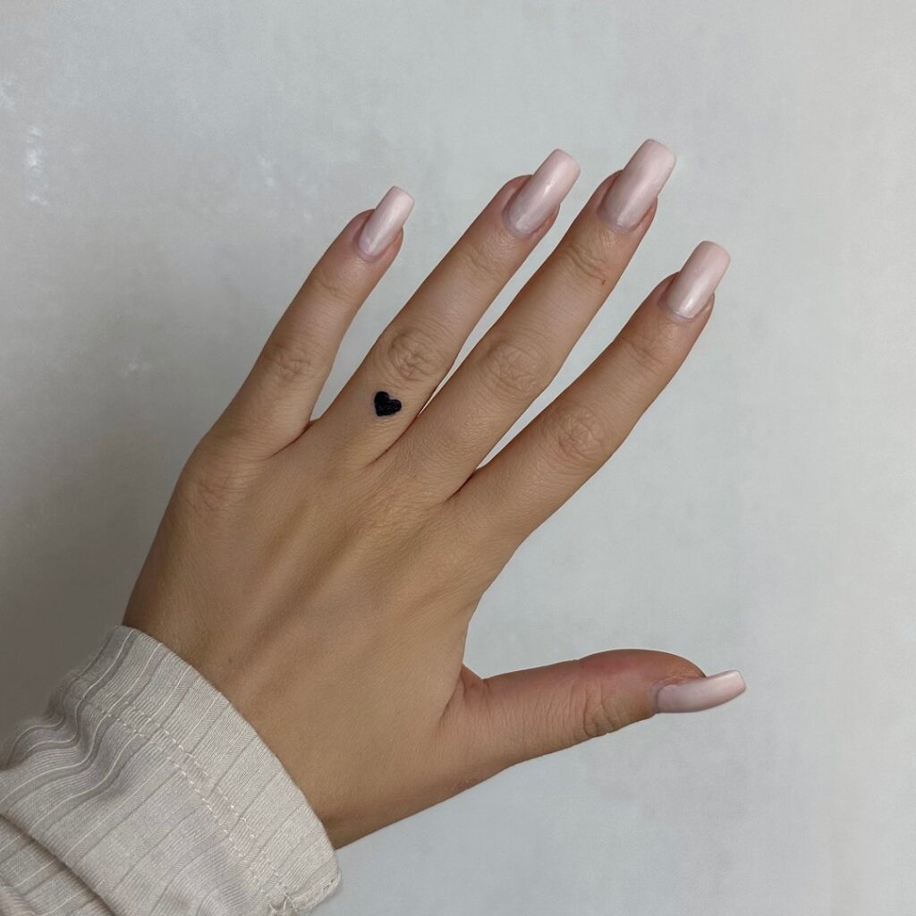 Tiny black love heart on ring finger tattoo