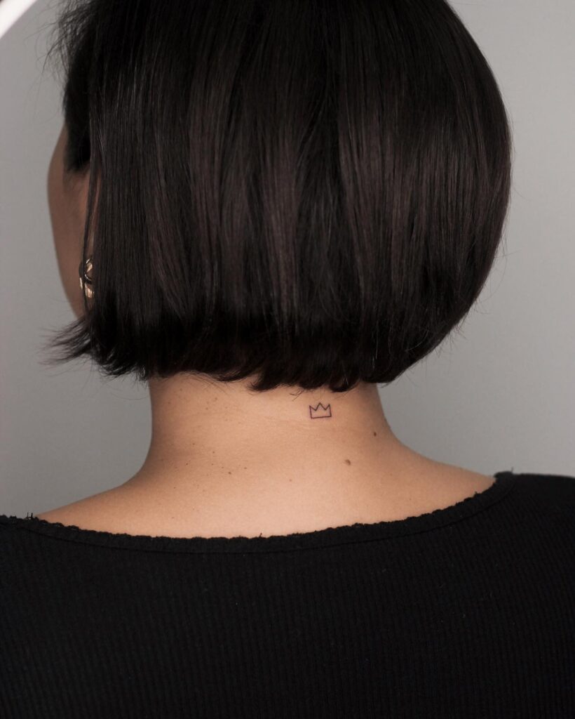 Tiny Crown Tattoo on the Back of the Neck for Females, a Delicate Outline: Miniature Majesty