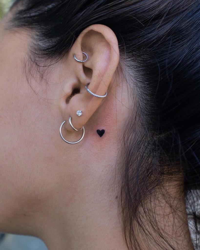 Tiny ear adornment black filled heart tattoo