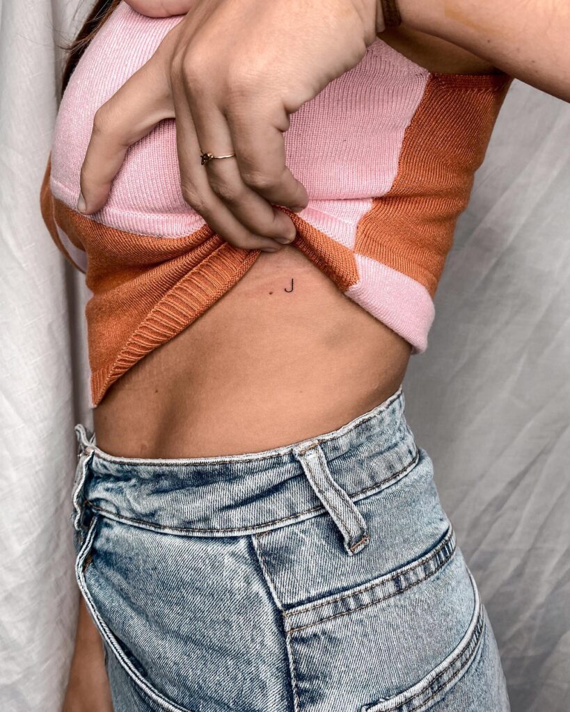 Tiny 'j' letter tattoo for females jewel of the ribs