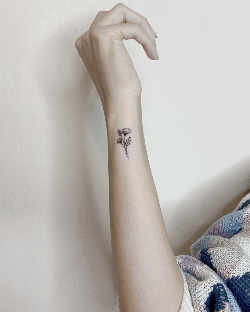 Tiny minimal tattoo on side wrist delicate flower accent