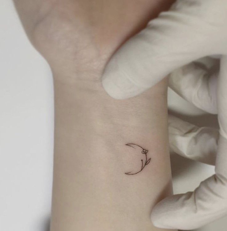 Tiny moon and flower tattoo a delicate celestial design
