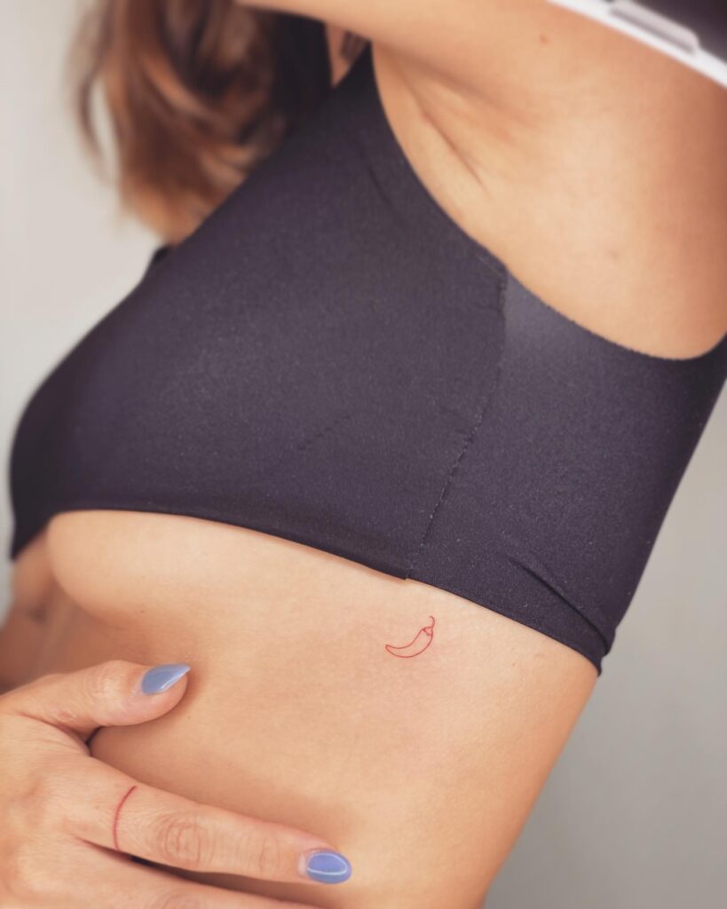 Tiny red chili pepper tattoo on the rib, adding a dash of playfulness spicy charm