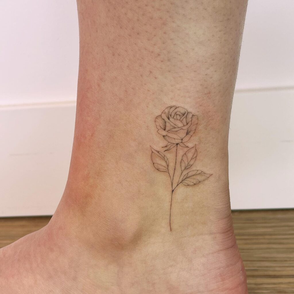 Tiny rose outline tattoo a subtle accent near the ankle ankle elegance