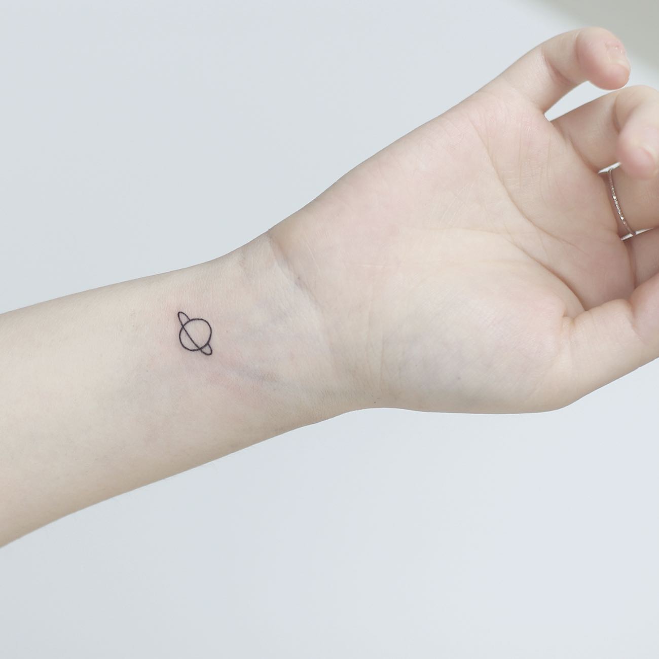 Tiny Saturn Planet Tattoo on Inner Wrist Cosmic and Minimalist Design for Women