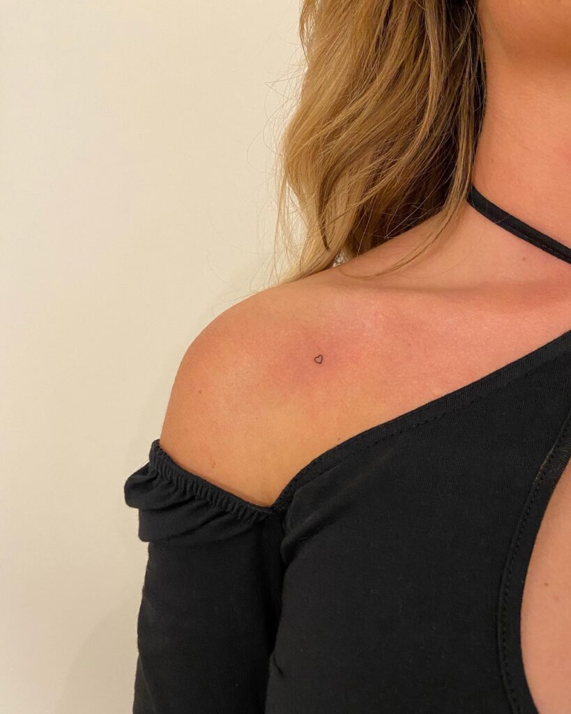 Tiny small love heart tattoo on the collarbone, a delicate symbol of affection dainty love beacon