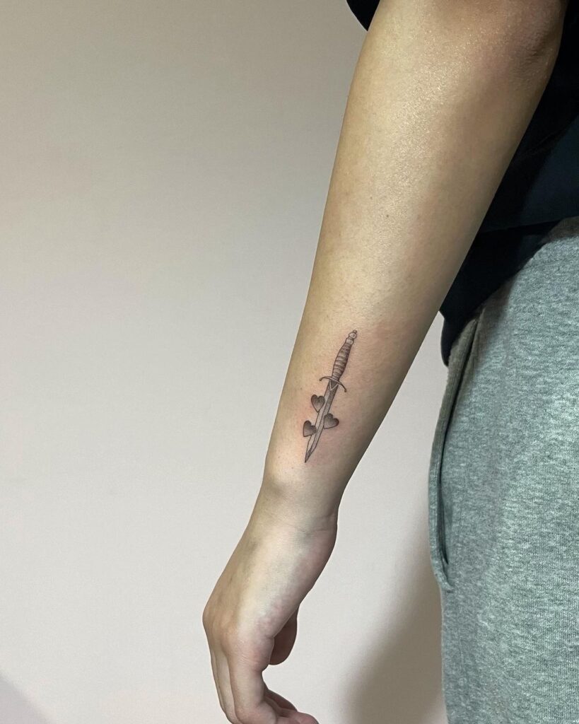 Tiny sword and hearts an endearing story in small outer wrist tattoo designs