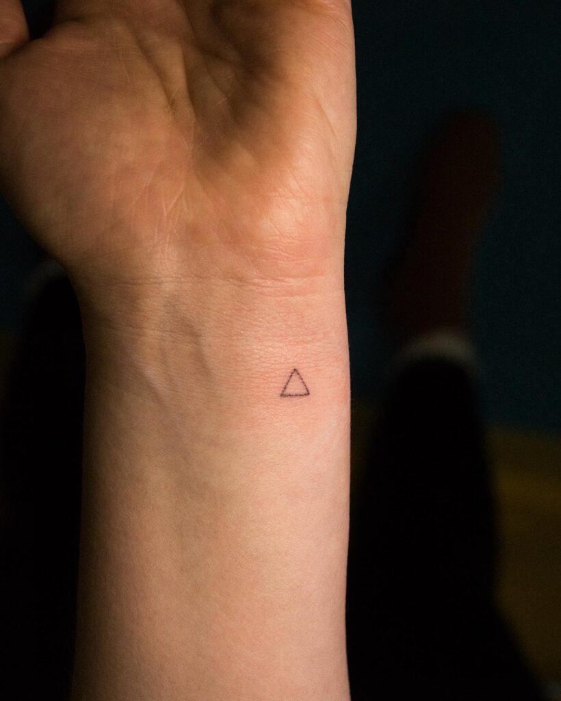 Tiny triangle tattoo on the inner side wrist, adding a touch of minimalist geometry: geometric whispers