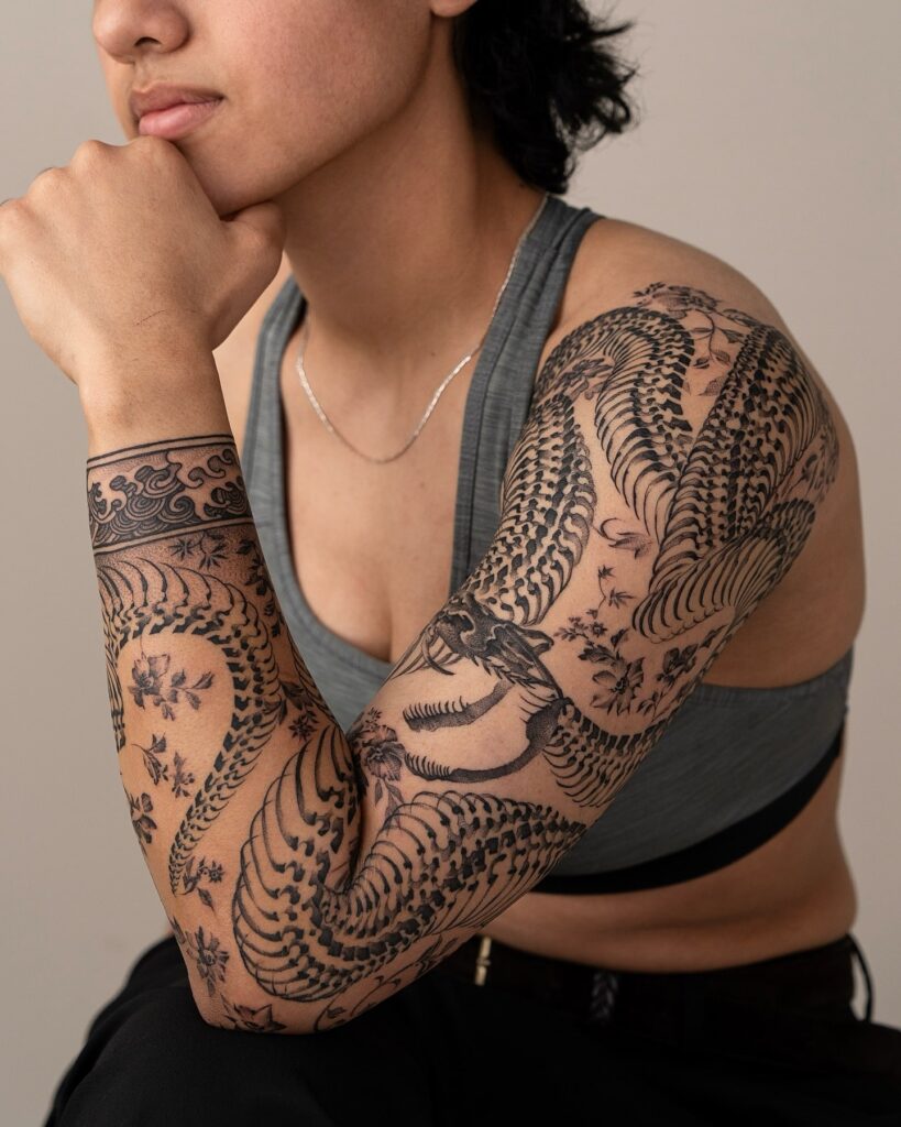 Traditional Japanese blackwork dragon tattoo sleeve with cherry blossoms