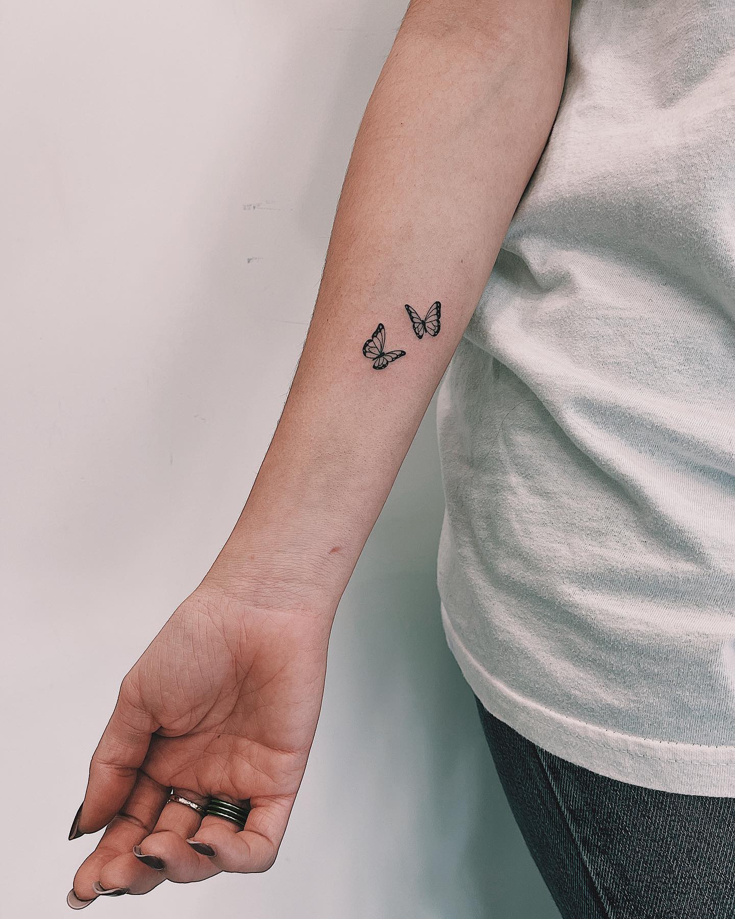 Two butterfly tattoo inner forearm with delicate linework and shading