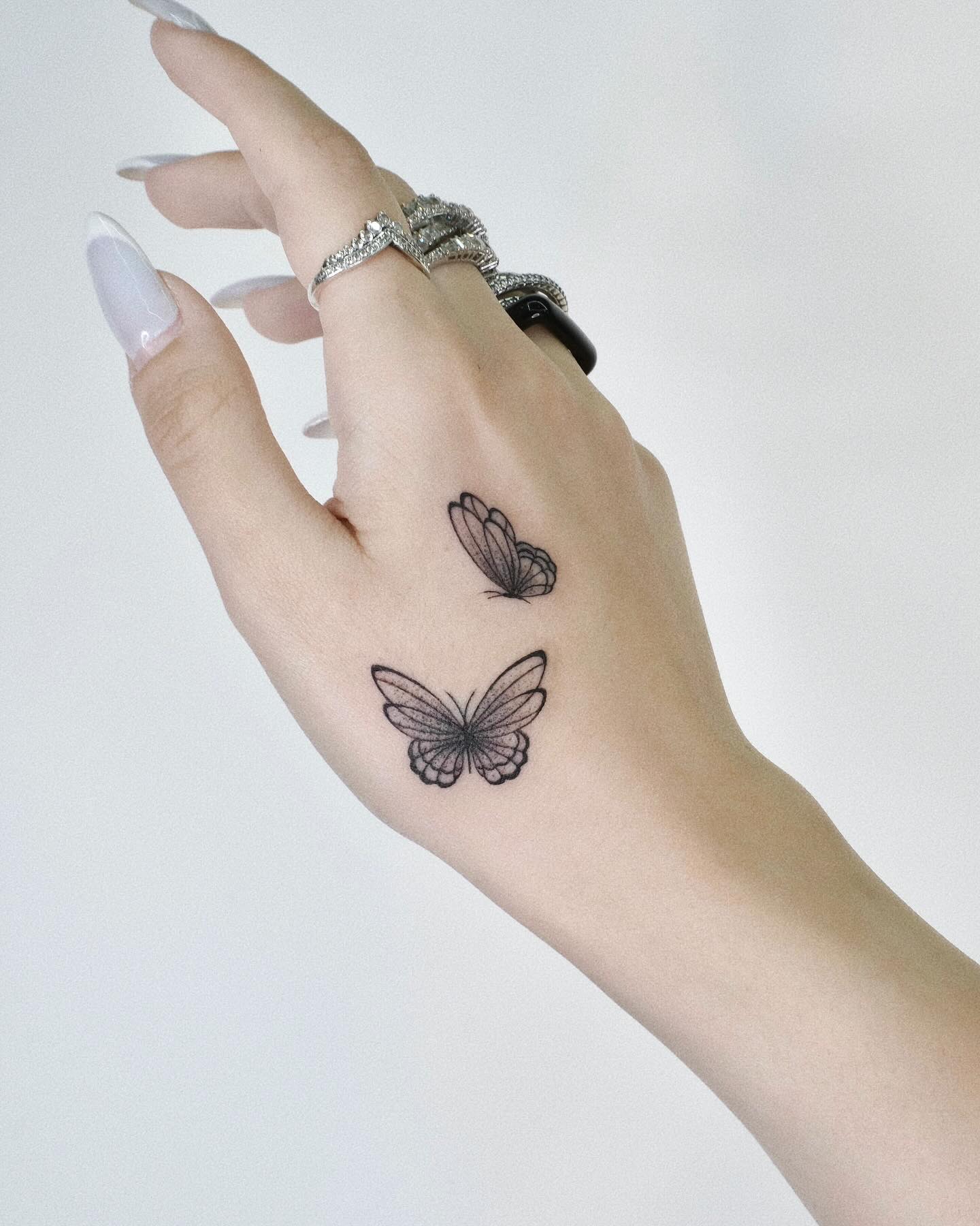 Two butterfly tattoo on back of hand in sketch style with fine detail