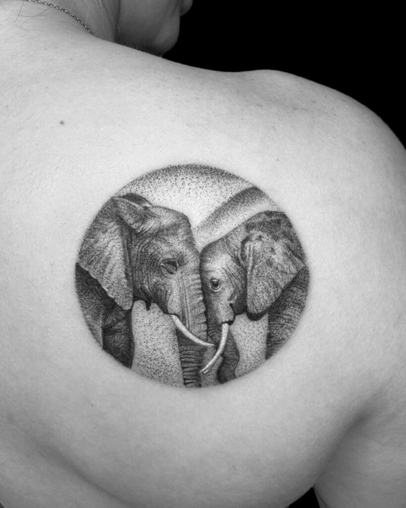 Two elephants gazing in grey shaded circle tattoo: shoulder elegance