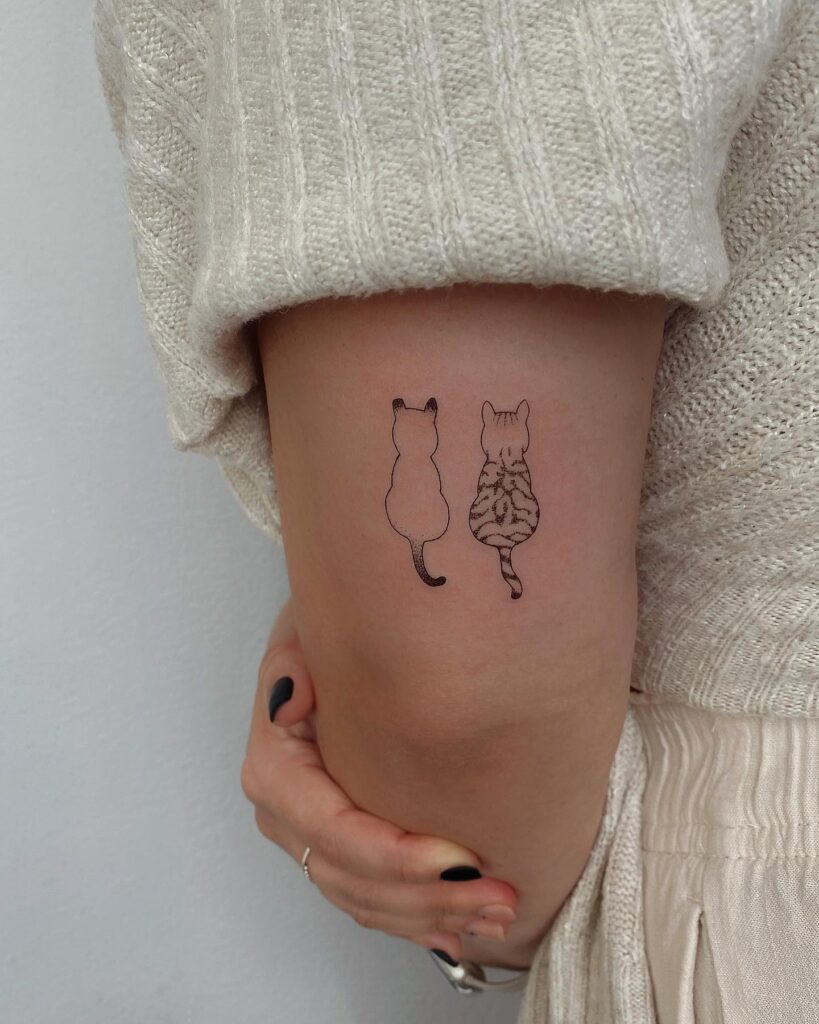 Two outline cats arm tattoo symbolizing companionship or pets