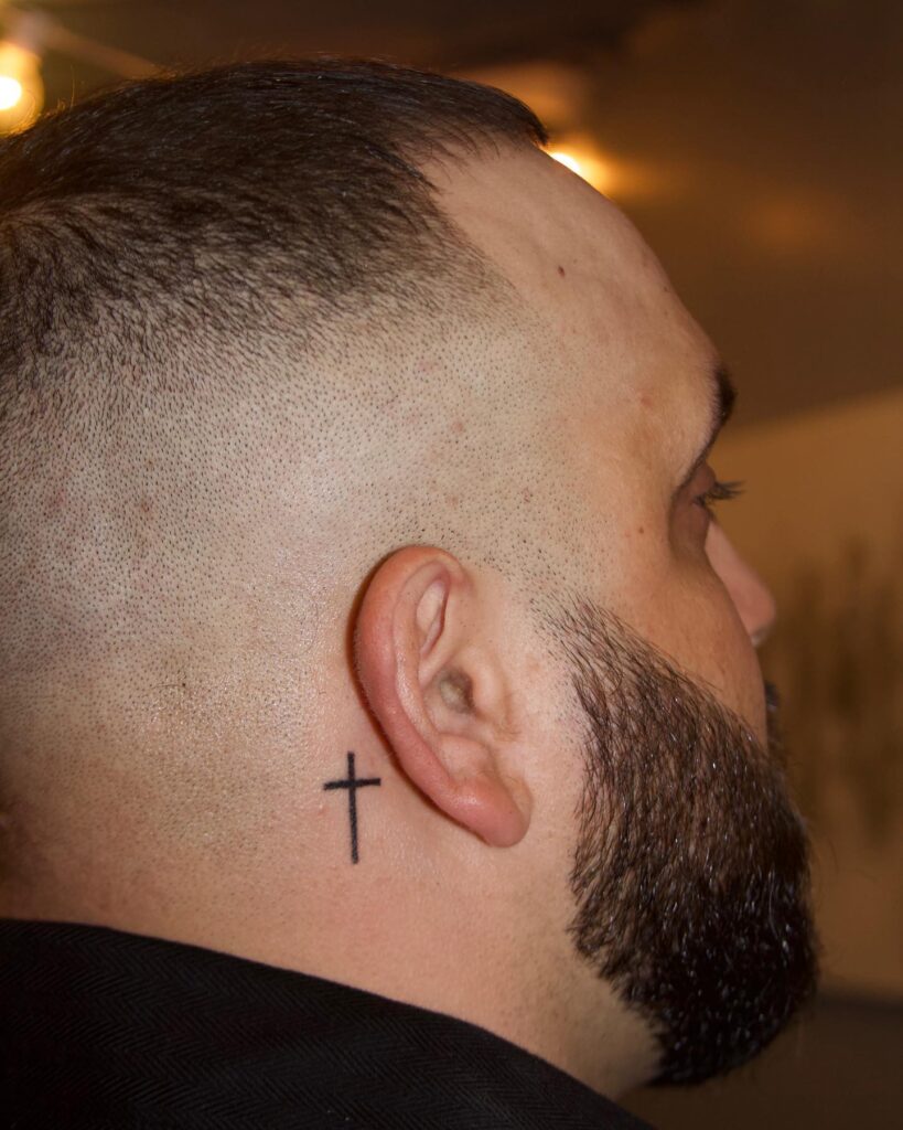 Unique Minimalist Cross Tattoo Behind the Ear for Men with image