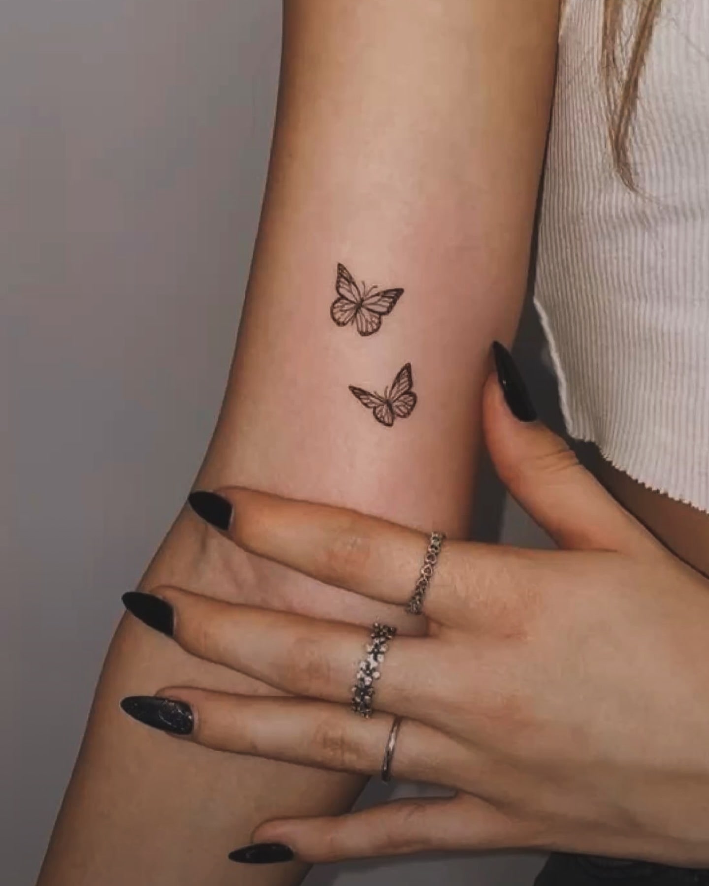 Upper forearm tattoo of two flying butterflies symbolizing shared growth