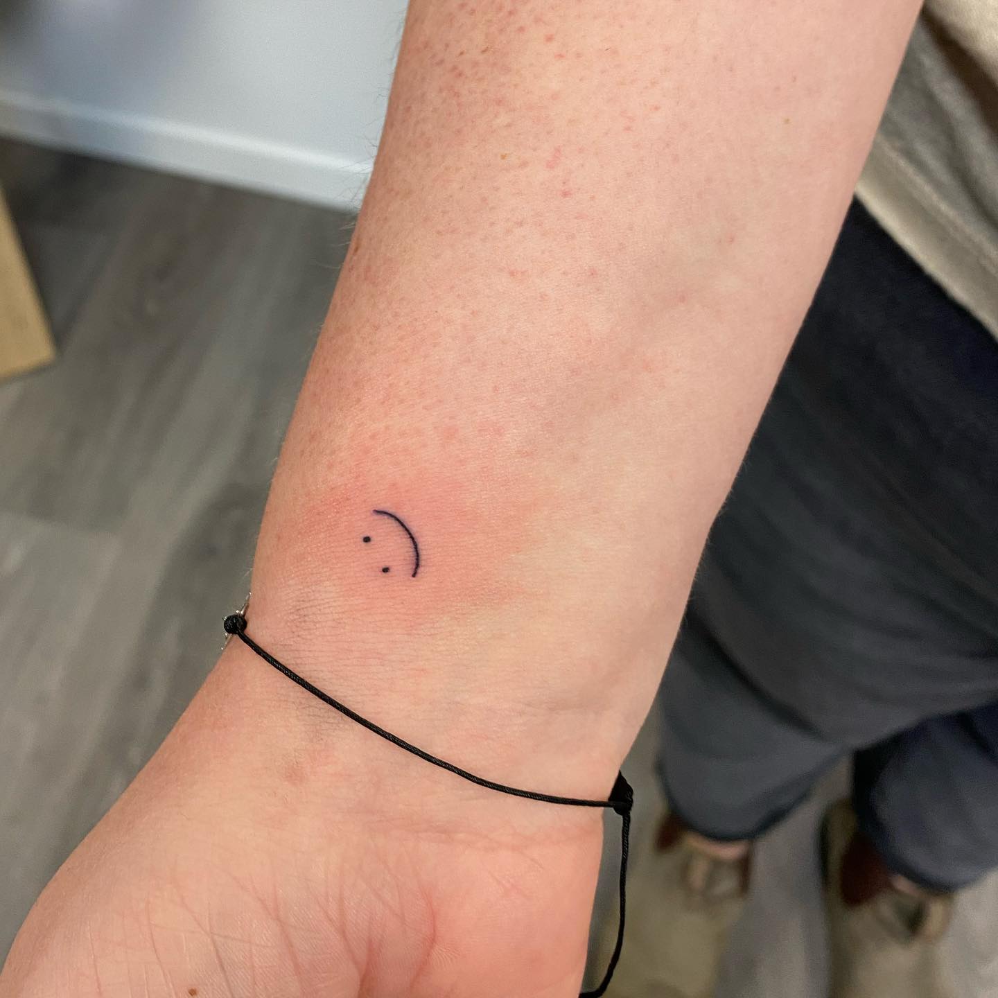 Upside-Down Smiley Face Wrist Tattoo Playful and Ironic Minimalist Design