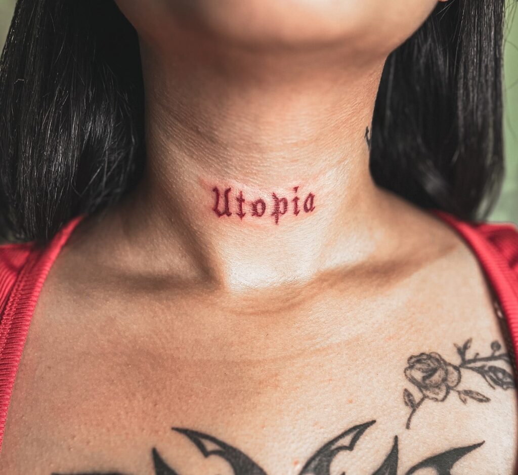 Utopia Red Gothic Lettering Tattoo on Neck Bold and Striking Design