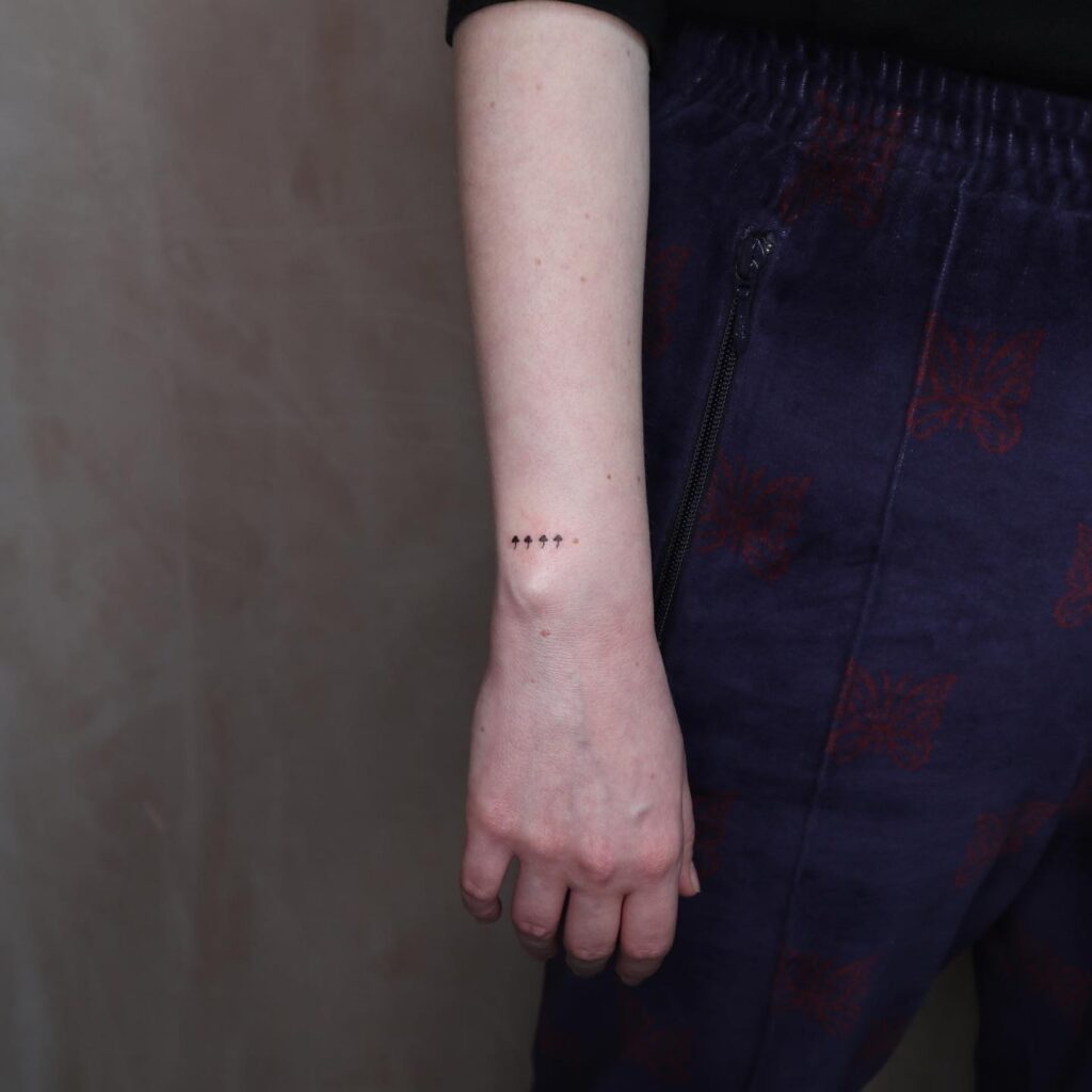Very Tiny Four Mushrooms All in a Row Tattoo on the Outer Side of the Wrist, Adding a Quirky Element: Mushroom Quartet