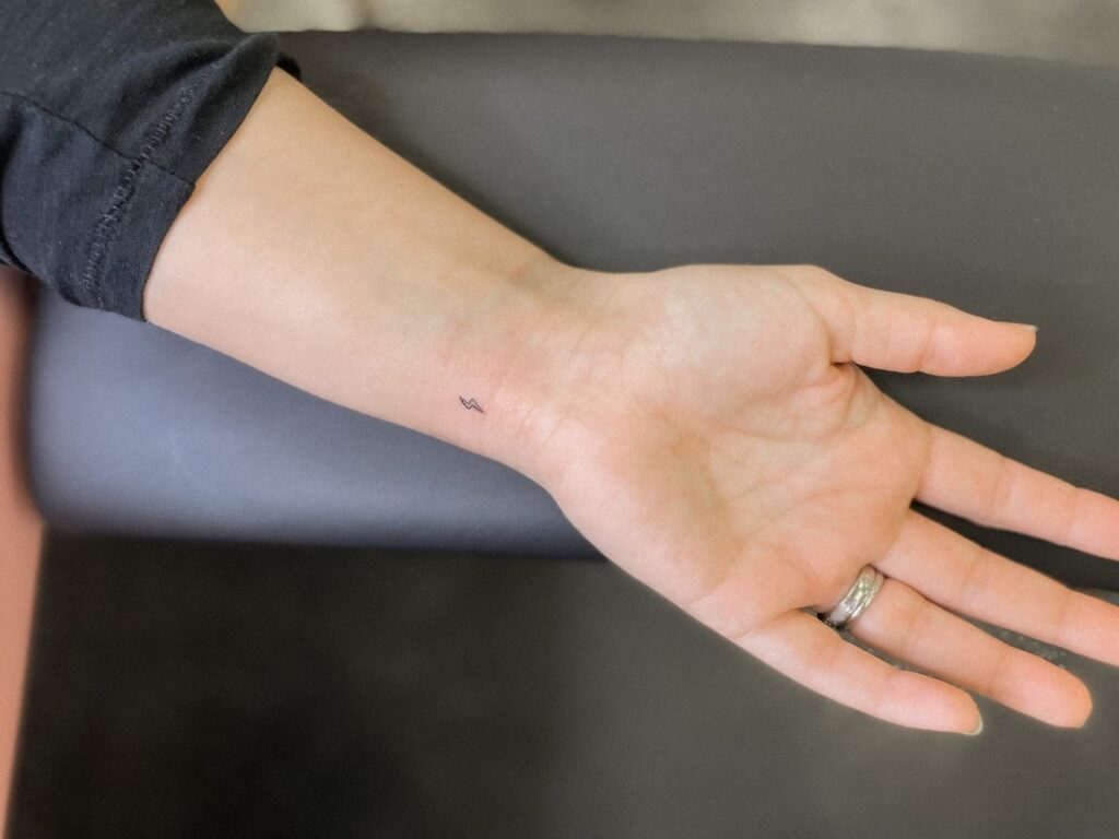 Very small outline lightning bolt tattoo on the wrist