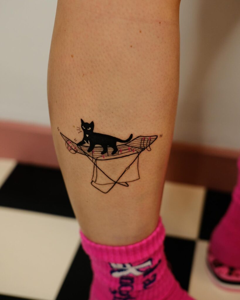 Whimsical black cat hammock tattoo with pink checkered fabric
