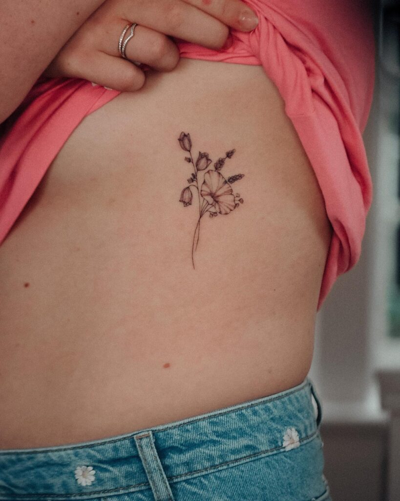 Wild flower tattoo adorning the side rib for a feminine touch-wild whimsy