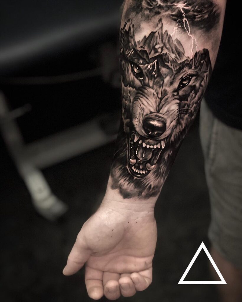 Wolf face and mountains tattoo on forearm majestic canine ink