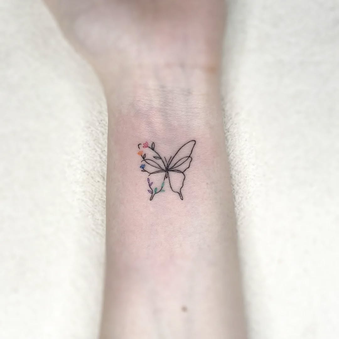 Wrist butterfly tattoo with colorful floral wing transformation