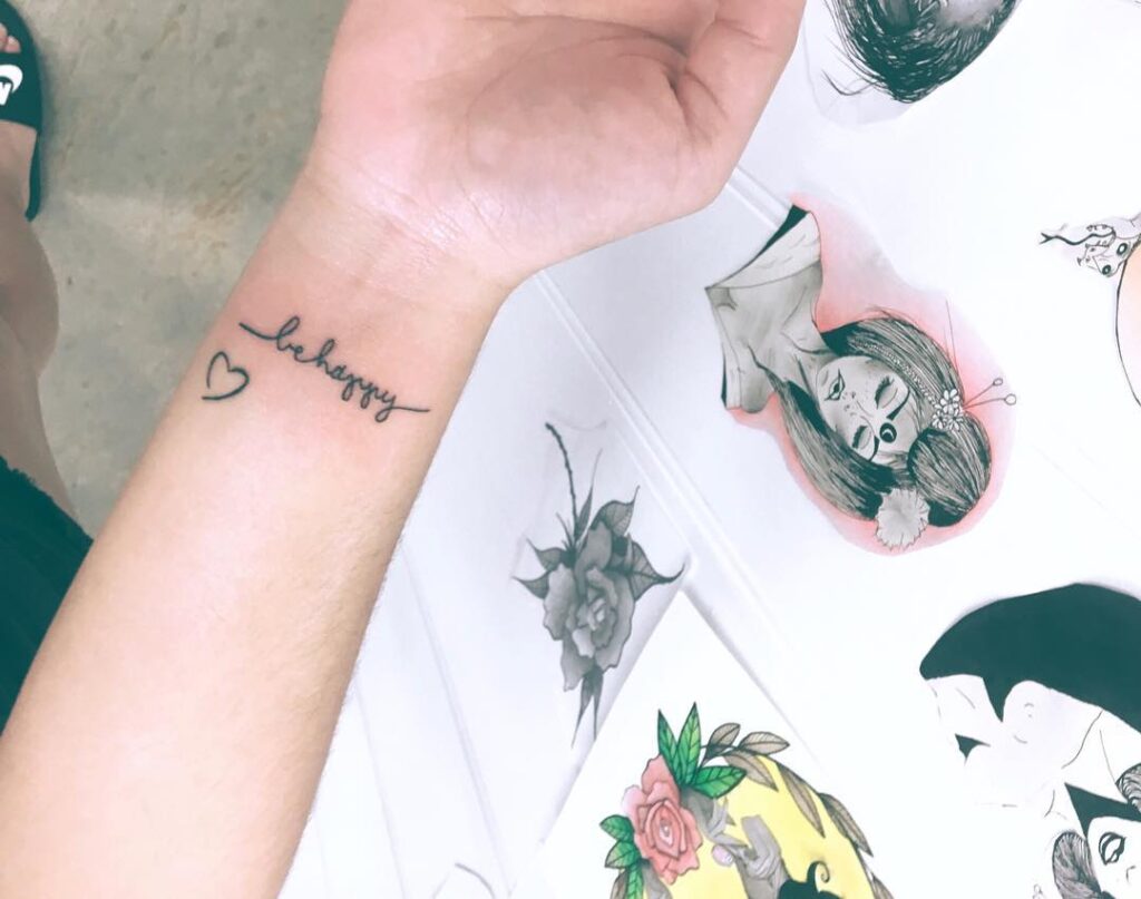 'be happy' text tattoo with outline heart on the wrist inspirational body art
