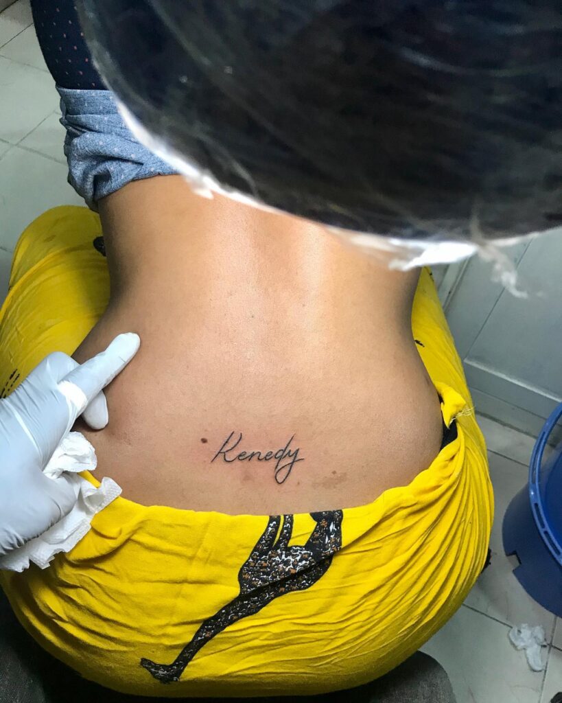 'Kenedy' Script Lettering Tattoo on the Lower Back: Personalized Beauty