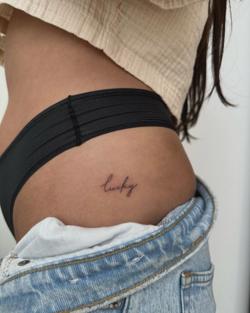 'Lucky' Text Script Lettering Handwriting Hip Tattoo, a Fortunate Adornment: Charm of Luck
