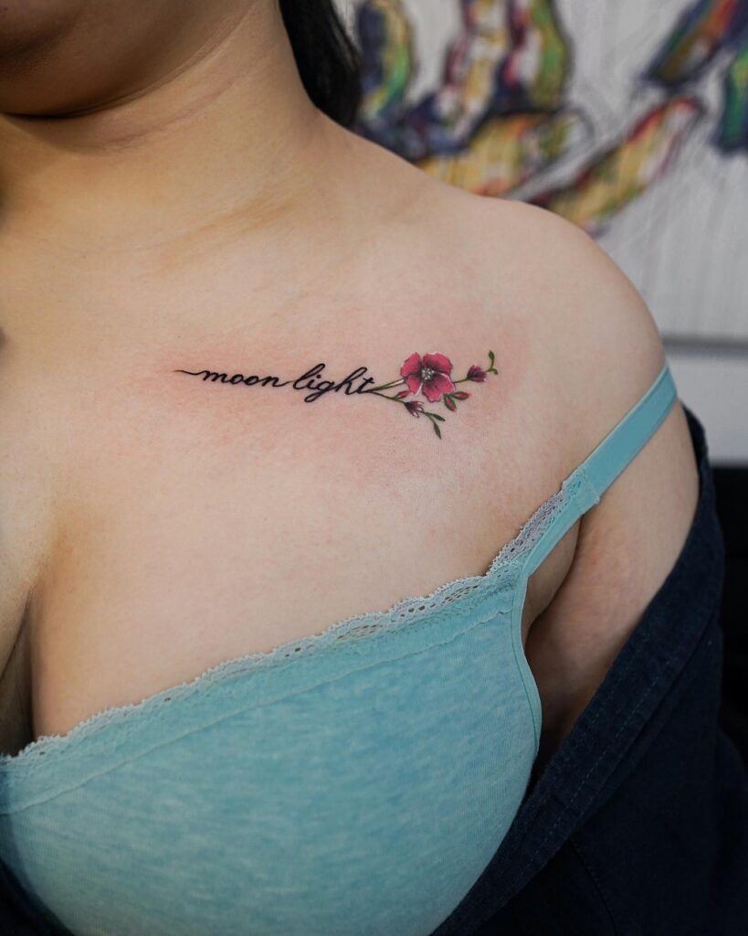 'moon light' word text tattoo on the collarbone with colorful flower accents, a celestial composition lunar elegance